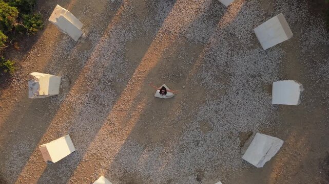 Vertical drone shot of a woman spinning at the center of the Crown of Limenaria in Thassos, highlighting symmetry and motion.