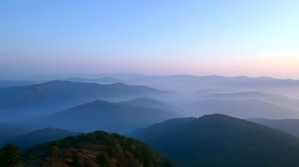 Fototapeta premium Misty mountain range bathed in soft golden light during sunrise creating a tranquil and ethereal landscape
