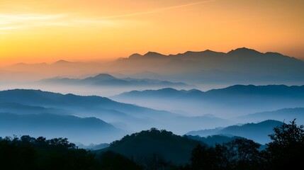 Obraz premium Misty mountain ranges bathed in the warm vibrant glow of sunrise or sunset create a serene and dramatic landscape view