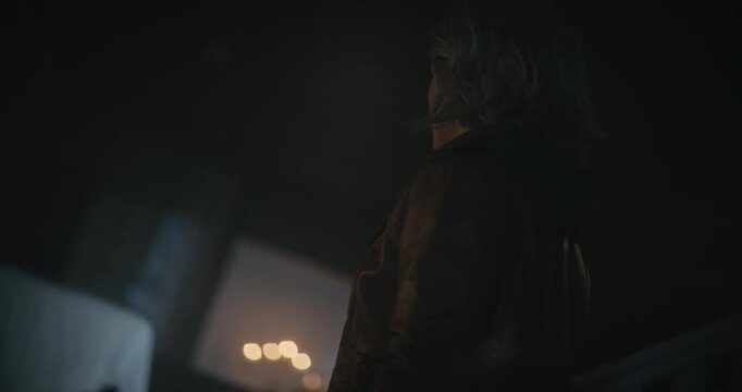 Frightened, alone woman with flashlight quickly looking around dark room - medium shot