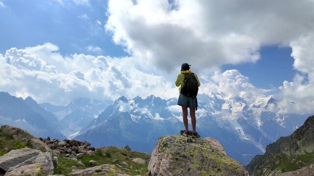 Hiker woman with backpack enjoying the breathtaking view of the mont blanc massif from a mountain top, appreciating the beauty of nature and the sense of freedom