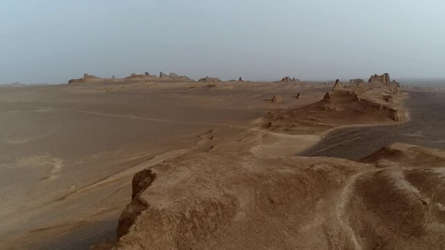 Yardang towers stand in hazy desert with wind erosion carving unique shapes creating atmospheric natural rock scene perfect for geology and wilderness stock video footage.