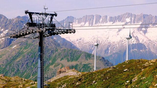 Overhead Cable Car and Beautiful Mountainscape with a Glacier and Wind Turbine in the Swiss Alps in a Sunny Summer Day in Andermatt, Uri, Switzerland.