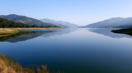 Fototapeta premium Mountain reflections shimmer across a calm body of water under clear daylight creating a serene and breathtaking natural landscape