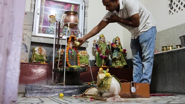 devotees performing abhishek ritual on shivling inside sacred temple environment