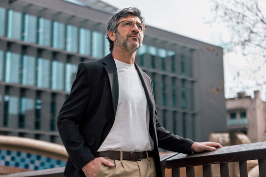 Confident mature businessman looking around while staying in front of an elegant office