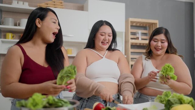 A group of three plus-size girls are having fun cooking together in the kitchen.