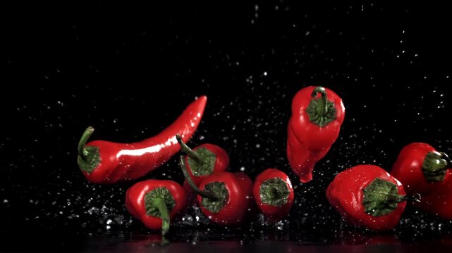 Studio wide red chilies flying through splash, energetic motion Filmed on a high-speed camera at 1000 fps.