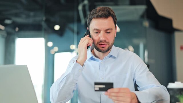 Close-up of stressed businessman or IT specialist explaining credit card issue on mobile phone. Frustrated corporate worker, manager or freelance designer contacting support service at office desk.