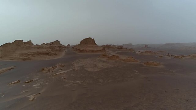 Single tall yardang tower rises in desert under overcast sky with wind erosion creating bold natural rock formation scene ideal for geology and landscape stock video content.