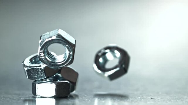 Closeup hex nuts on reflective countertop, stacked balance Filmed on a high-speed camera at 1000 fps.