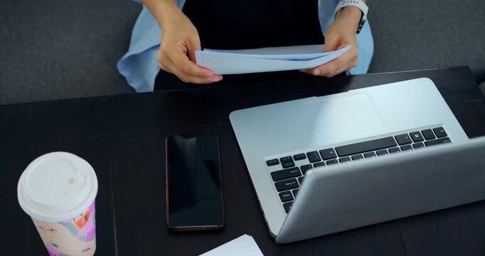 Hands sorting papers beside laptop, preparing contract and final notes steady gestures flip pages, point to clauses, and arrange signatures next to phone and coffee cup on neat desk, conveying