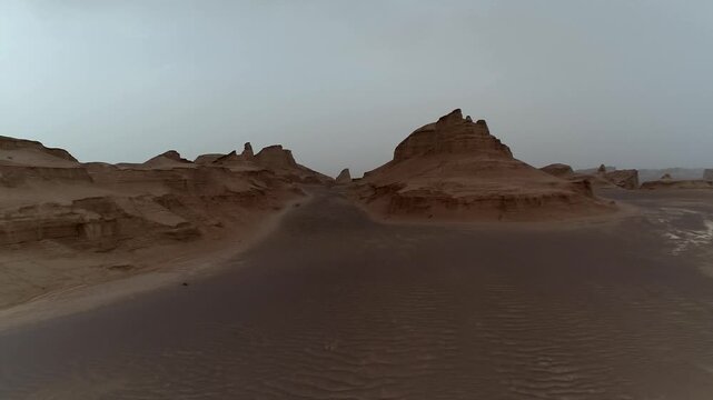 Isolated yardang formation in empty desert under overcast sky with wind erosion creating minimalist natural rock scene ideal for geology and landscape stock video content.