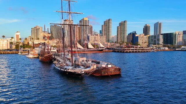 San Diego bay, CA, USA and city skyline, with historic sailing ships in aerial view on warm summer evening