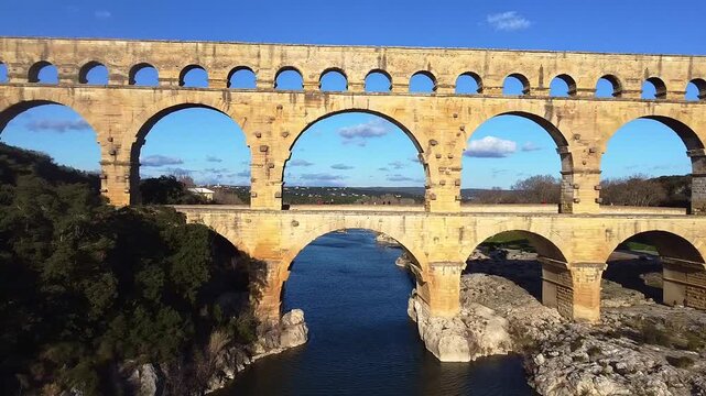 Pont du Gard. Gard Bridge. Roman aqueduct bridge over the river. Aerial view dolly out. The tallest Roman bridge in the world, with three levels of arches. Remoulins. France.