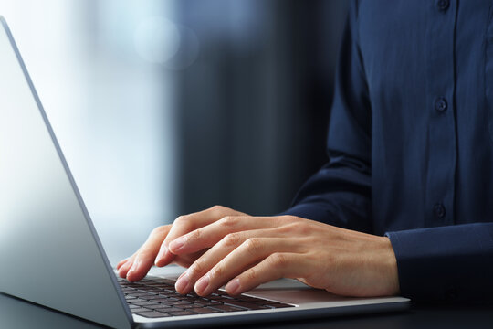 Businessman using laptop computer at desk in office. Closeup of hands and keyboard. Business technologies.