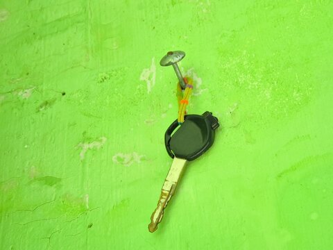 Motorcycle key hanging on a nail against a bright green wall background