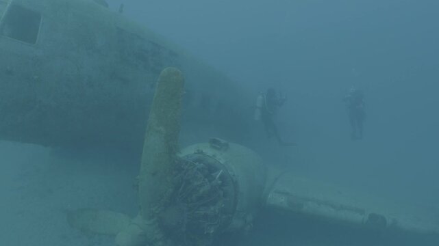 log footage of air plane wreck underwater  fish around ocean scenery of airplane and metal on ocean floor  scenery scuba divers to explore c47 dakota airplane