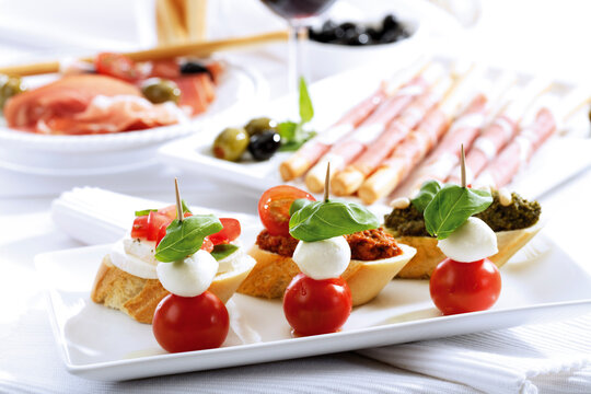 Grissini with parma ham and olives and mozzarella with tomatoes, italian starters