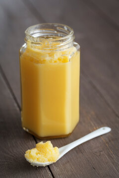 Jar of butter on wooden table, close up