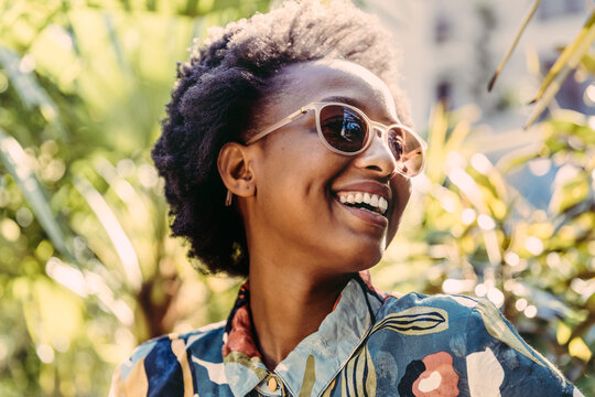 Portrait of happy young woman wearing sunglasses in garden