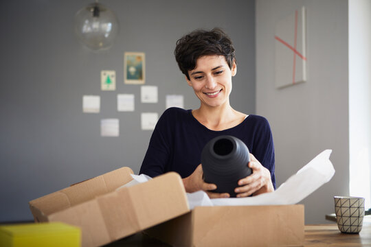 Smiling woman unpacking parcel at home