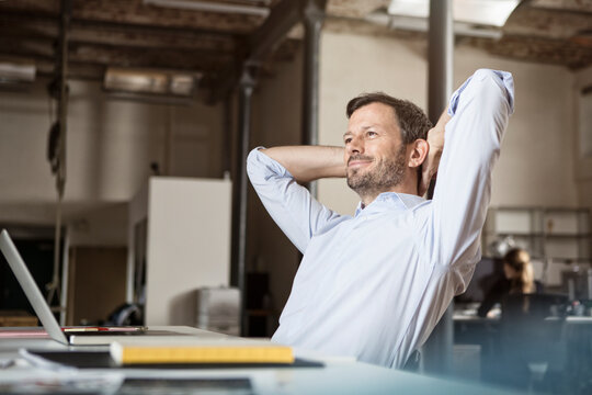 Confident businessman at desk leaning back