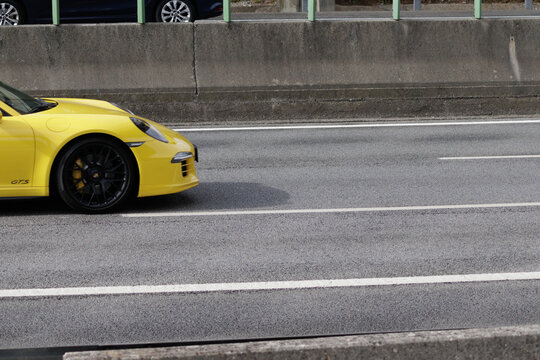 Yellow porsche 911 gts driving on highway