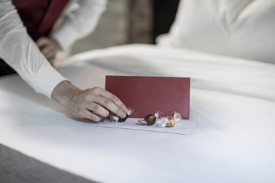 Housekeeper putting chocolates on hotel bed