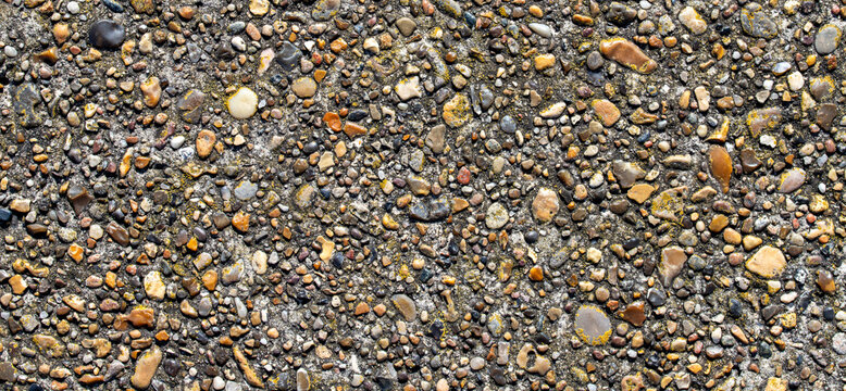 Exposed aggregate concrete pavement surface with small colorful river pebbles texture background for architectural design