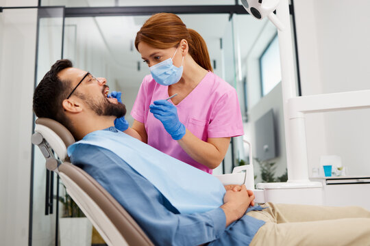 Female dentist providing oral health check-up to a male patient in a modern dental clinic