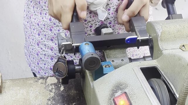 Locksmith copying a key using an automatic key cutting machine
