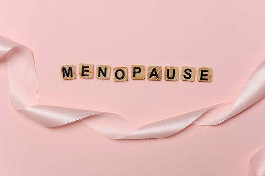 Menopause word with pink ribbon on pastel background for women healthcare awareness concept