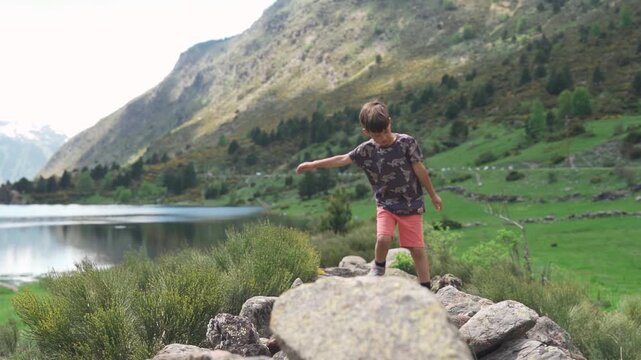 Child walking on rocks by mountain lake
