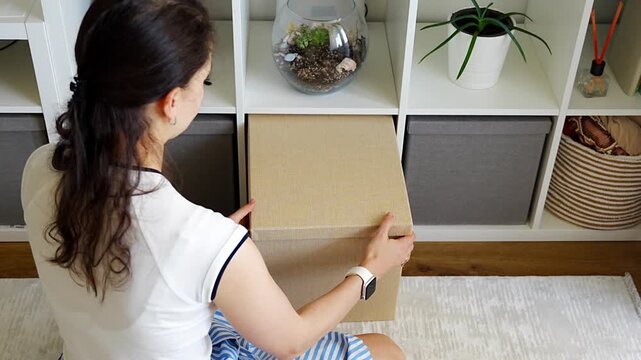 Young woman using storage box from shelving system in home interior. Home organization and decluttering routine concept