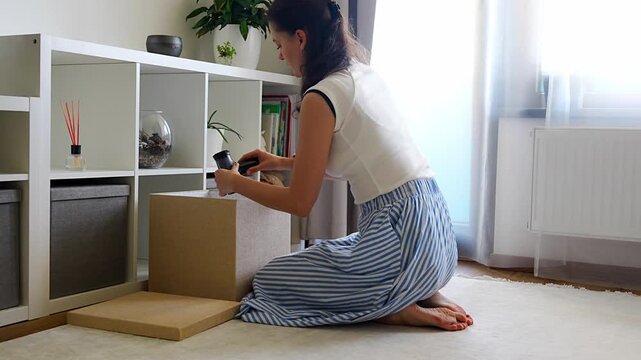 Young woman looking for things in storage box, organizing belongings in modern home interior. Home organization and decluttering routine concept