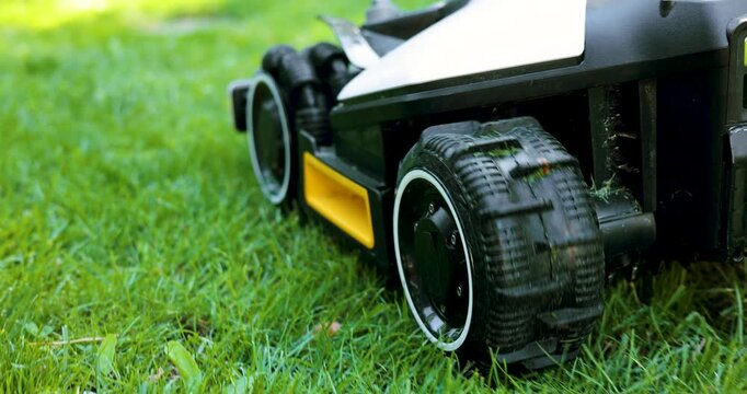 closeup of robotic lawn mower working at garden cutting lush green grass