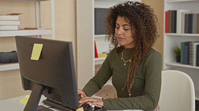 Woman typing at computer with hands on keyboard in home office while later raising an index finger; concentration.