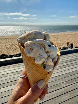 Close-up of a woman standing by the sea holding traditional Danish ice cream cone on a sunny spring day, Hjerting, Esbjerg, Jutland, Denmark