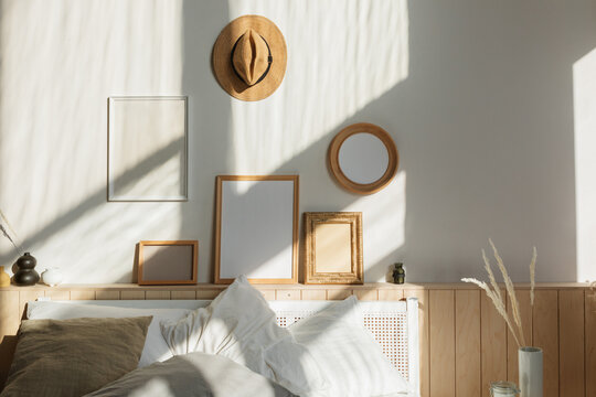 Cosy sunlit bedroom with natural shadows on a collection of assorted blank picture frames hanging over a double bed
