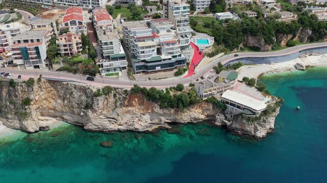 Aerial video following a winding seaside road carved along the steep limestone cliffs of southern Vlora, Albania