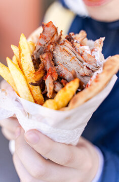 Close-up of a boy standing in the street eating a traditional Greek Gyros wrap