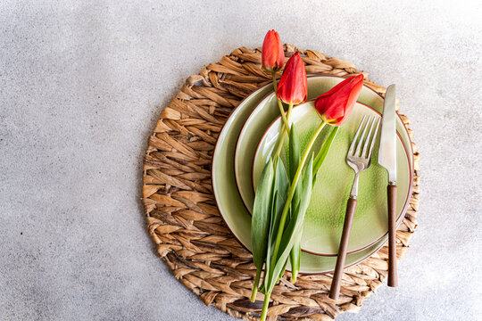 Overhead view of a rustic Spring place setting on a table with red tulips