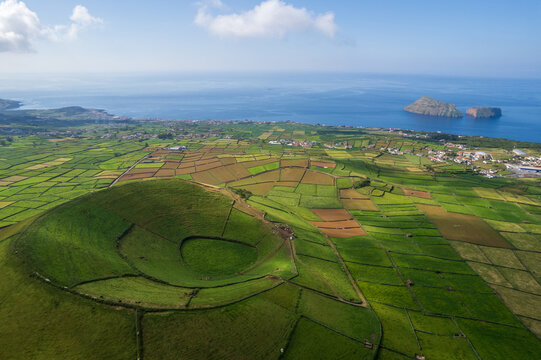 Aerial view of Terceira islans in Azores, Portugal. Volcanic landscape.  Drone shot of ancient Pico Dona Joana volcano and  cabras islet. Green fields in rural environment.