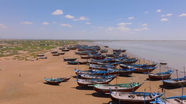 Aerial view of Damb beach in Balochistan showing beached fishing boats lined along an arid shoreline.