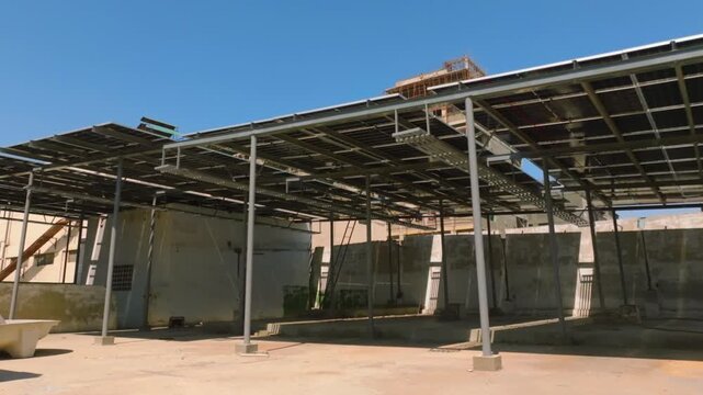 Solar panel array mounted on steel frame above factory courtyard in Karachi