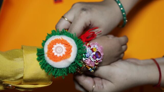 sister tying colorful rakhi bracelet on little brother wrist during raksha bandhan