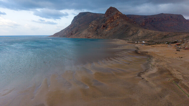 Remote beach and rocky mountains under cloudy sky