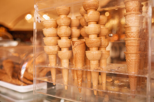 Close-up of stack of assorted crispy waffle ice cream cones stacked in a transparent display case at an Italian gelateria