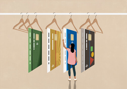 Young woman shopping, looking at different credit cards on display hangers
